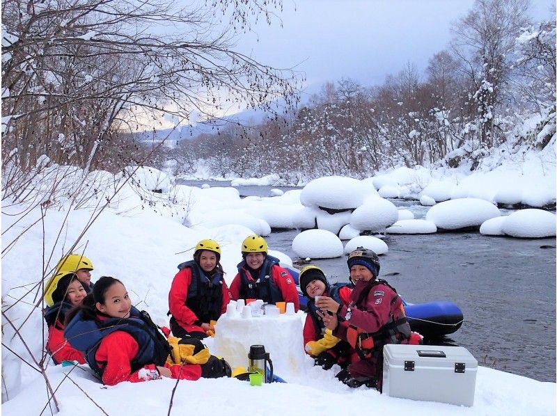 ニセコアクティビティ　冬におすすめ　スノービューラフティングツアー　雪上ティータイム　川岸に上陸してホットドリンクを楽しむ人々　アドベンチャースマイル★Adventure　Smile