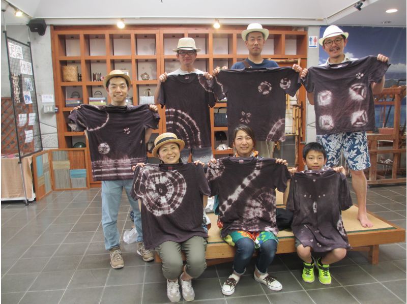 People taking a commemorative photo with the mud-dyed work they experienced at the “Oshima Tsumugi and Experience Yumeori no Sato” on Amami Oshima