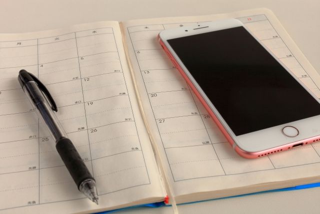 Schedule book, pen and smartphone