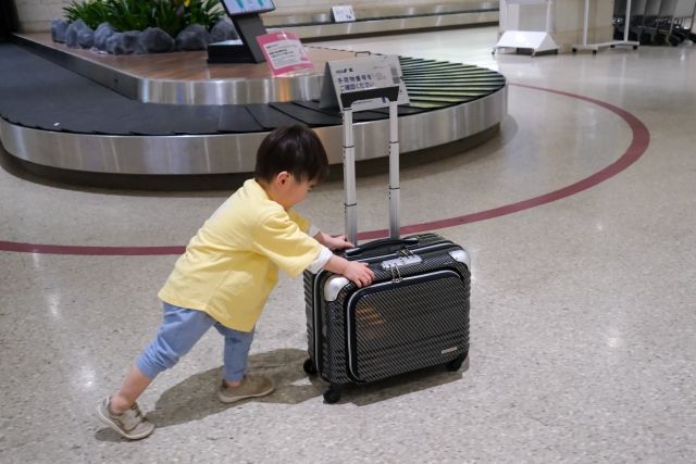 空港でスーツケースを押す男の子