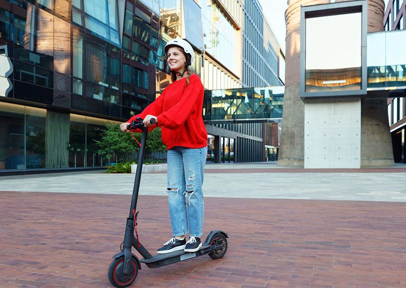 電動キックボード　電動キックスケーター　原動機付自転車　電動モーター　欧米　普及　レンタル　シェアリングサービス　移動手段　観光　電動キックボードに乗る外国人女性　ヘルメット　料金