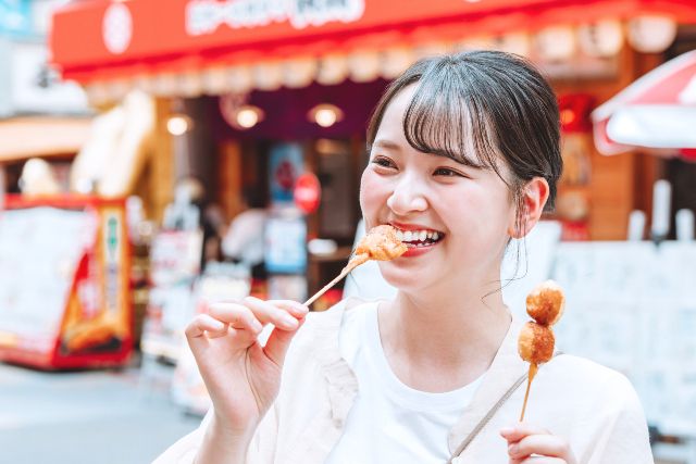 大阪　新世界　串カツを食べる女性