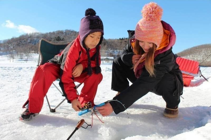 Parents and children enjoying smelt fishing on the ice