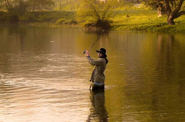 A man fishing in the river in the evening