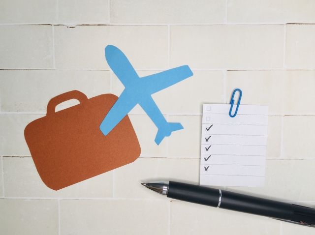 กระดาษและปากกาเพื่อทำรายการจัดกระเป๋าเดินทางของคุณ