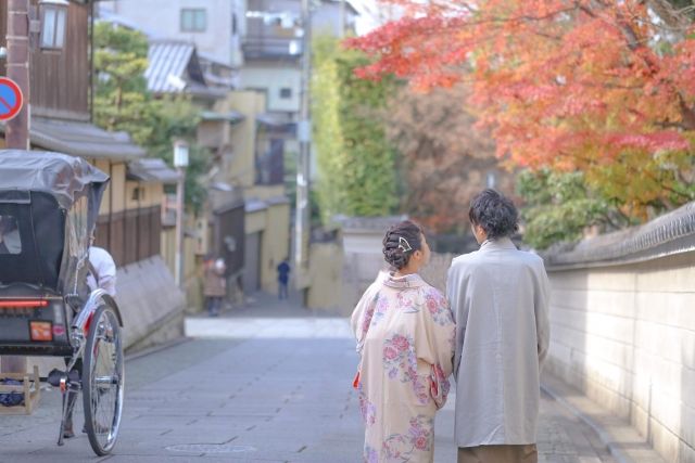 A couple strolling around Kyoto in kimono and enjoying the autumn leaves