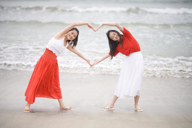 波打ち際でハートのポーズをとる若い女性たち