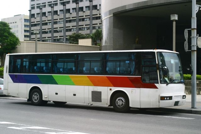 A rainbow-colored tourist bus runs through Okinawa Prefecture