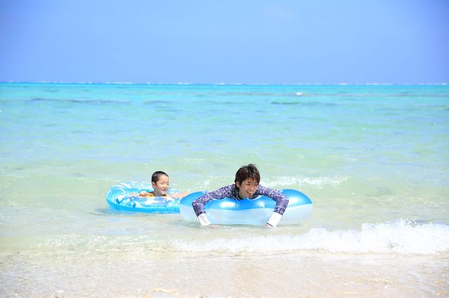 家長和孩子在沖繩海裡享受游泳的樂趣