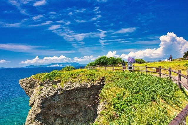沖縄　万座毛　観光スポット　絶景を楽しんで歩く人々
