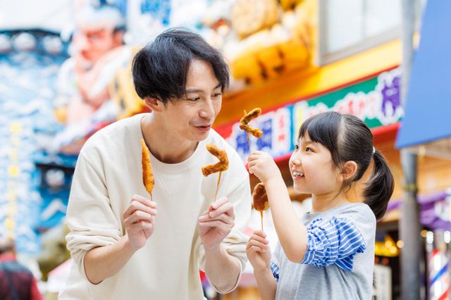 Parents and children enjoying eating kushikatsu in Osaka