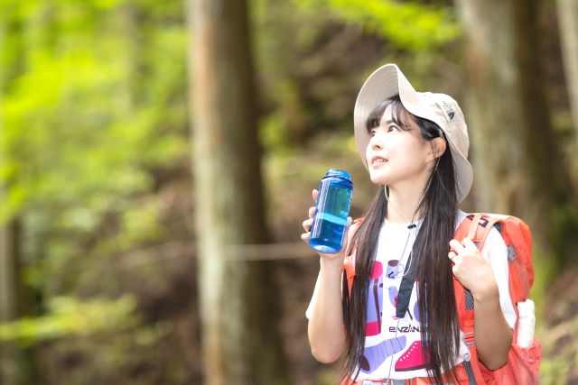 A woman who hydrates during mountain climbing / hiking