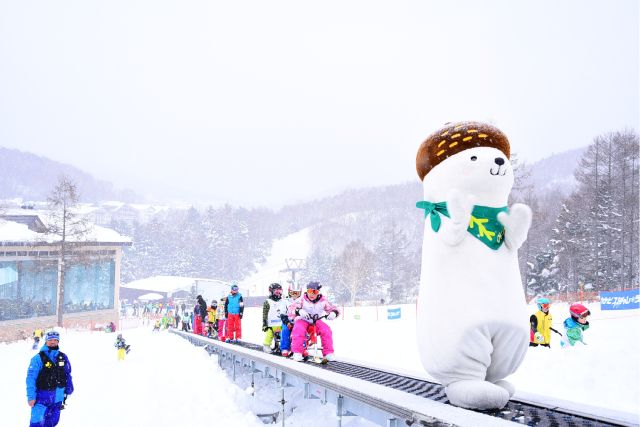 Shiga Kogen Tourism PR character “Okomin” and children playing on the family slope at Yakebiyama Ski Resort