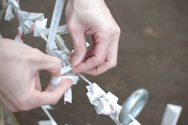 A person's hand tying a fortune-telling fortune to a fortune-telling table