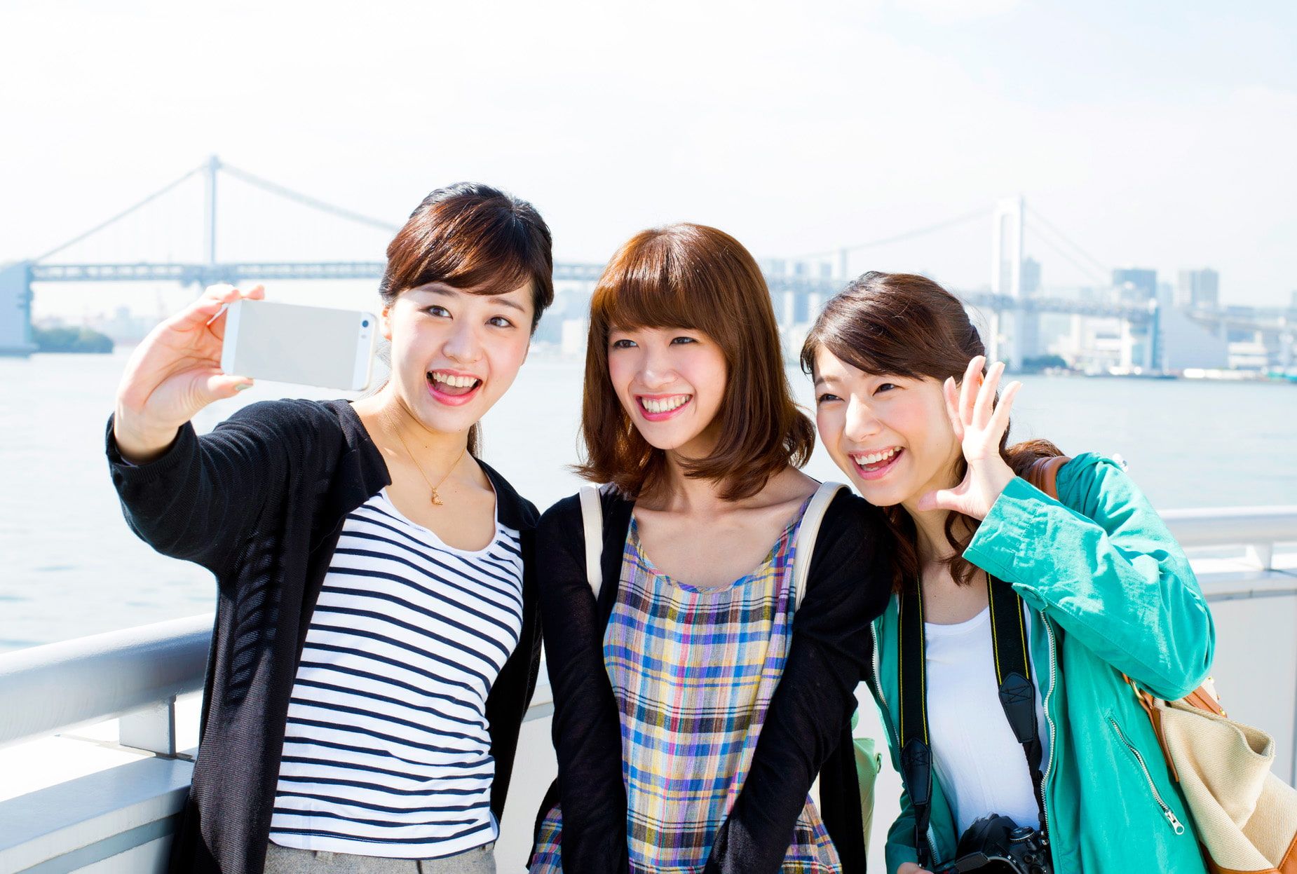 東京　1泊2日モデルコース　定番観光　人気スポット　お台場　レインボーブリッジを背景に写真を撮る女性たち　東京観光を楽しむ女子旅