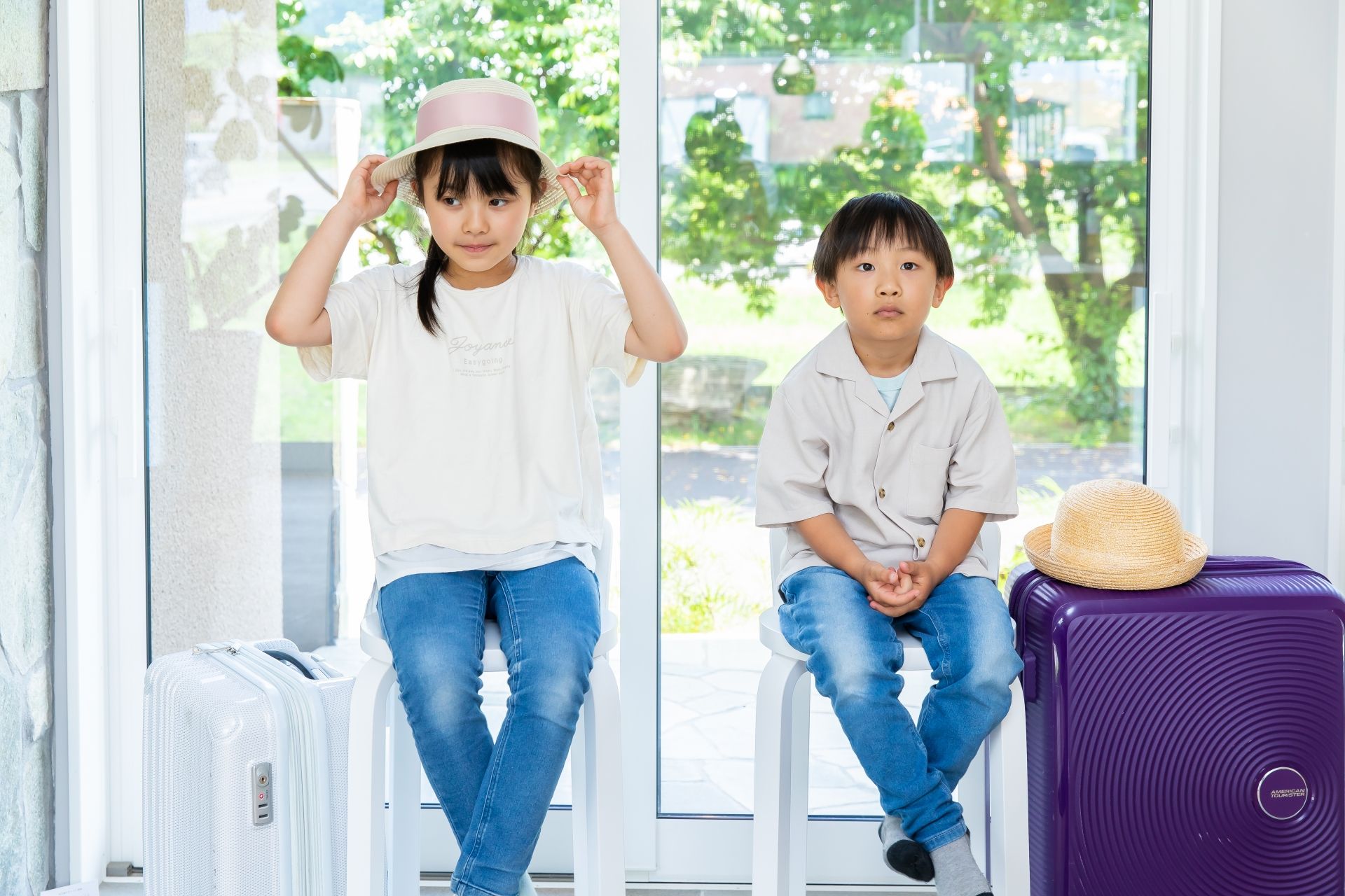 Photo of a travel suitcase next to two children