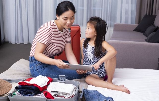 Parents and children preparing for a trip while checking luggage on a tablet