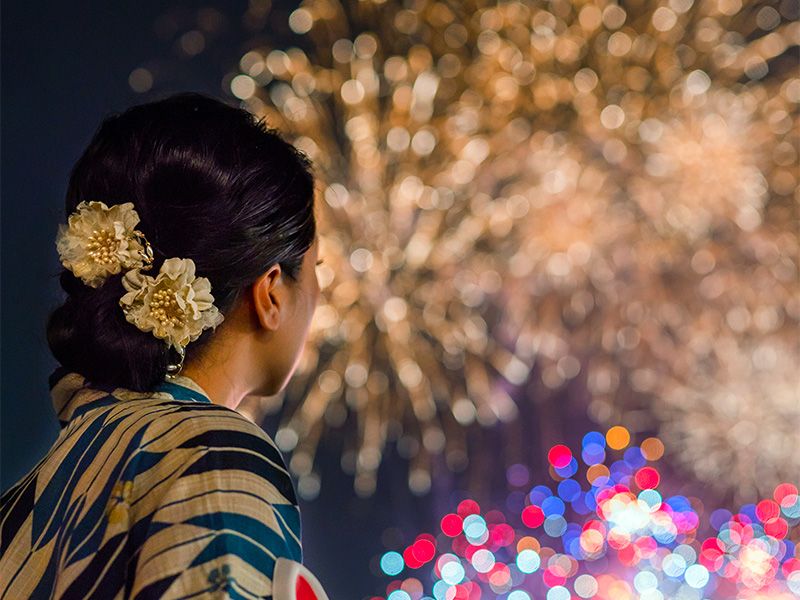 ผู้หญิงในชุดยูกาตะกำลังดูดอกไม้ไฟ